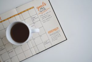週間予定を書き込んだ手帳とカレンダーが置かれたデスク