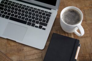 机の上のノートとコーヒーで一息つく様子