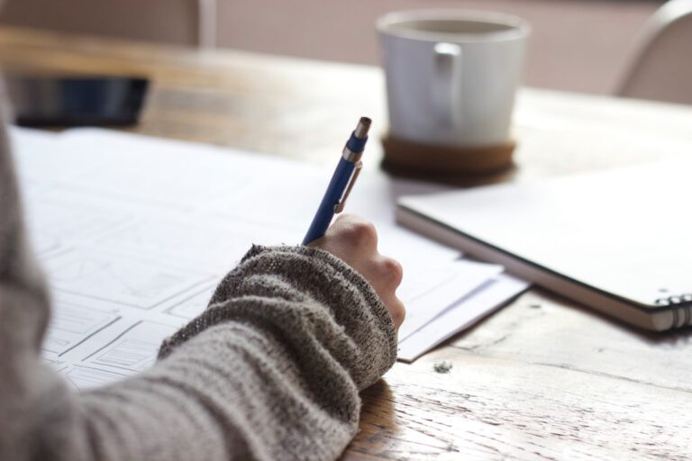 紙にページの構成を書き出して並べ替えている様子