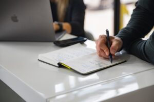 机の上でノートに書き出しながら打ち合わせをしている様子